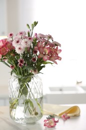 Photo of Vase with beautiful flowers on table in kitchen. Stylish element of interior design