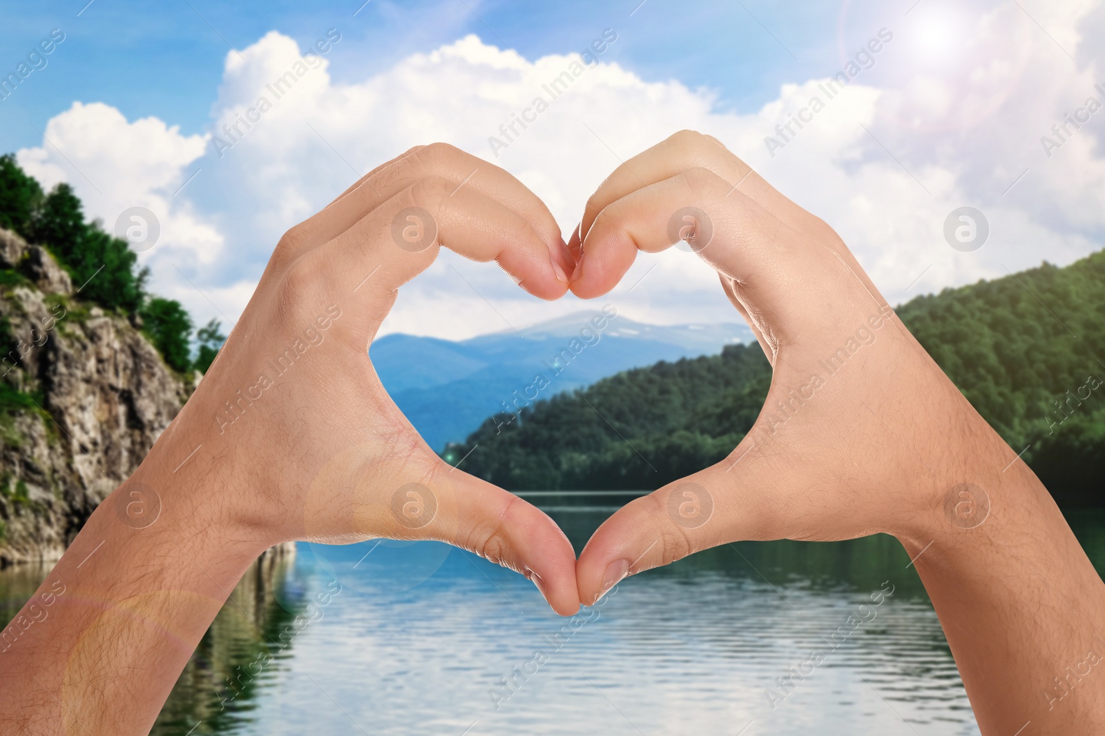 Image of Man making heart with hands near lake on sunny day, closeup