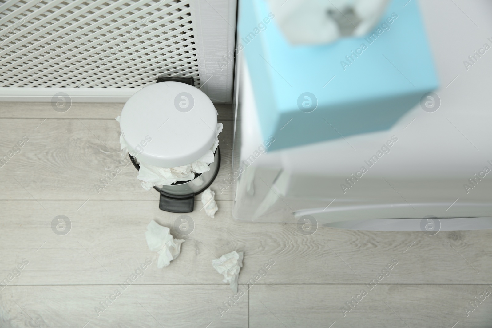 Photo of Used paper tissues and trash can on wooden floor, above view