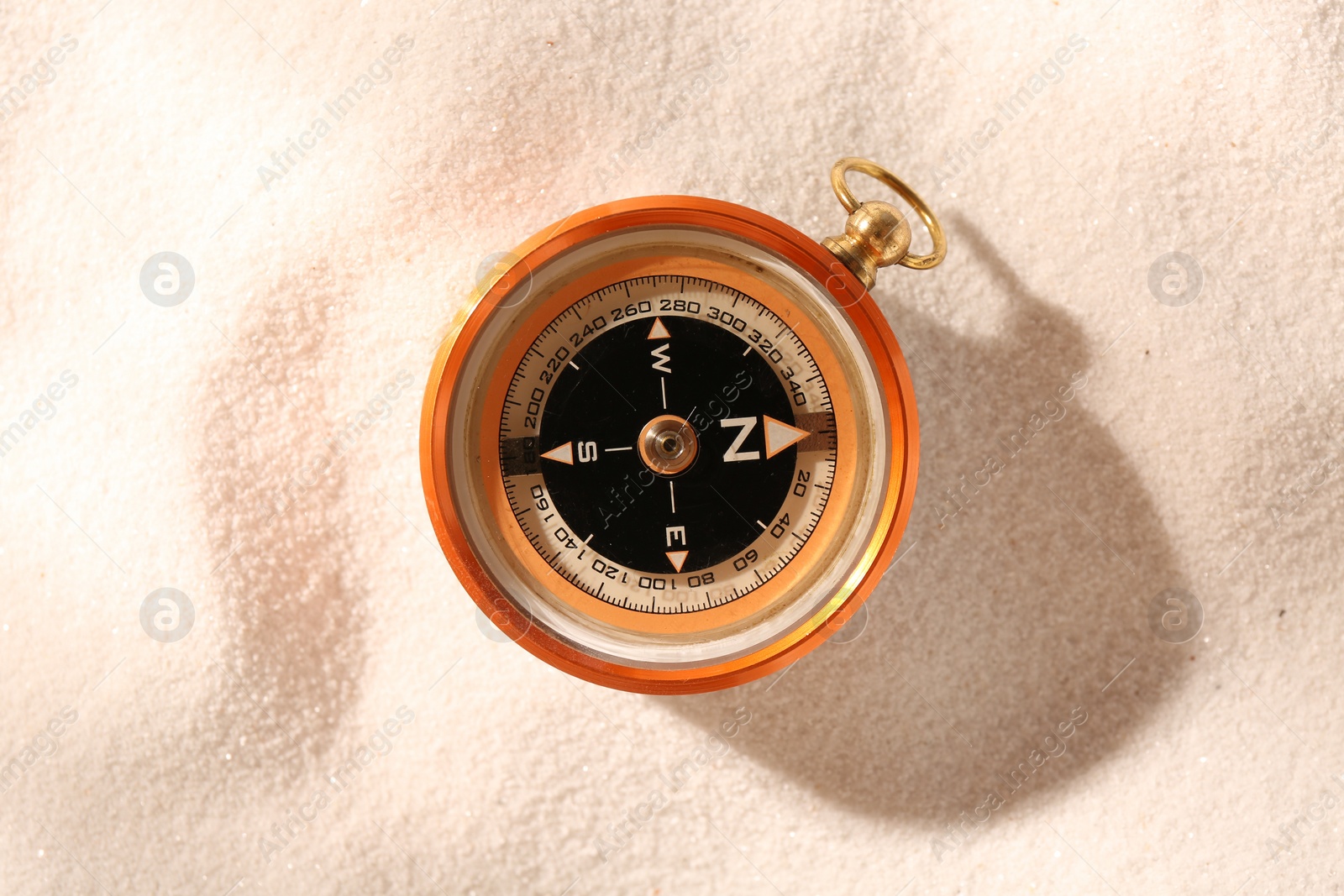 Photo of Compass on sand, top view. Navigation equipment