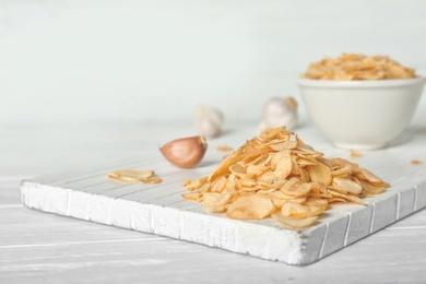 Photo of Dried garlic flakes on white wooden board