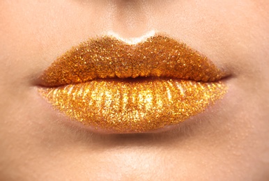 Beautiful young model with golden lips makeup, closeup