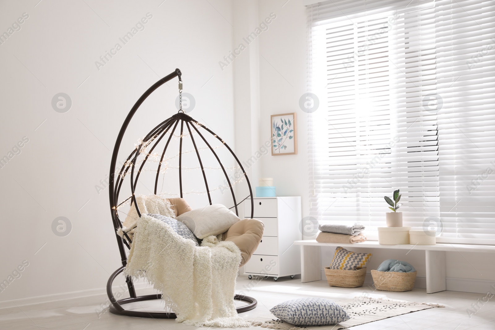 Photo of Cozy hanging chair with fairy lights in modern living room. Interior design