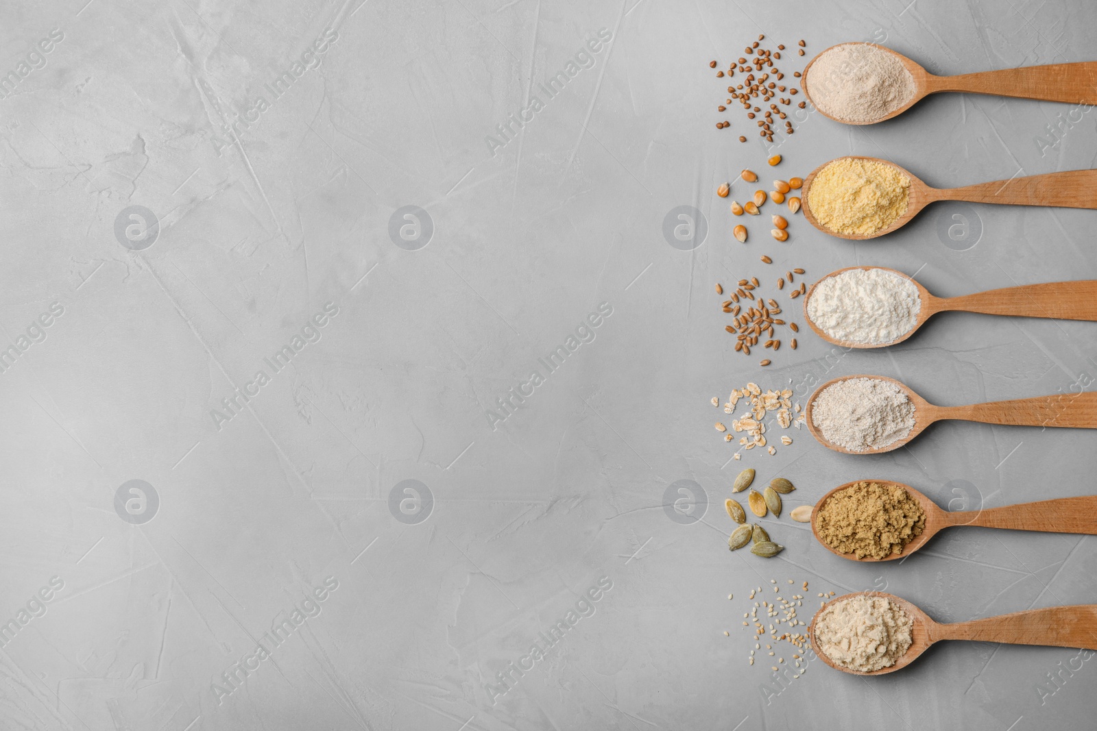 Photo of Spoons with different types of flour on gray background