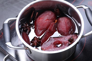 Tasty red wine poached pears and spices in pot on grey table, closeup