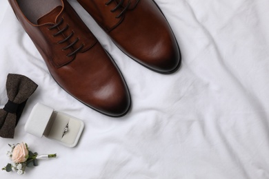 Photo of Flat lay composition with wedding shoes on white fabric, space for text