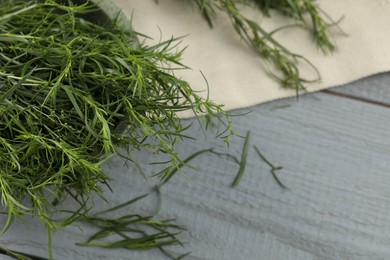 Photo of Fresh tarragon leaves on grey wooden table, closeup. Space for text