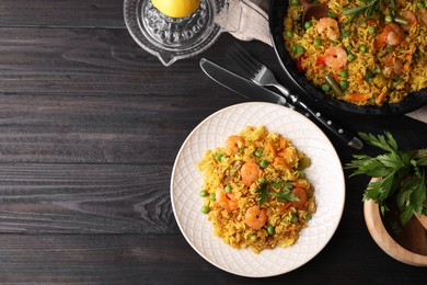 Photo of Tasty rice with shrimps and vegetables served on dark wooden table, flat lay. Space for text