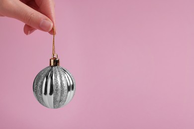 Woman holding silver Christmas ball on pink background, closeup. Space for text