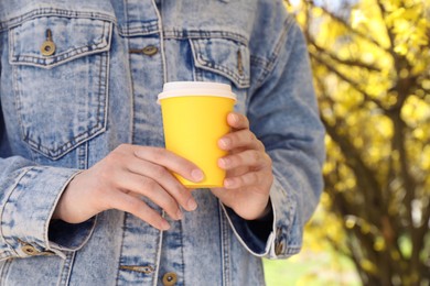 Woman with paper cup of coffee outdoors on sunny day, closeup