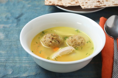 Bowl of Jewish matzoh balls soup on color wooden table