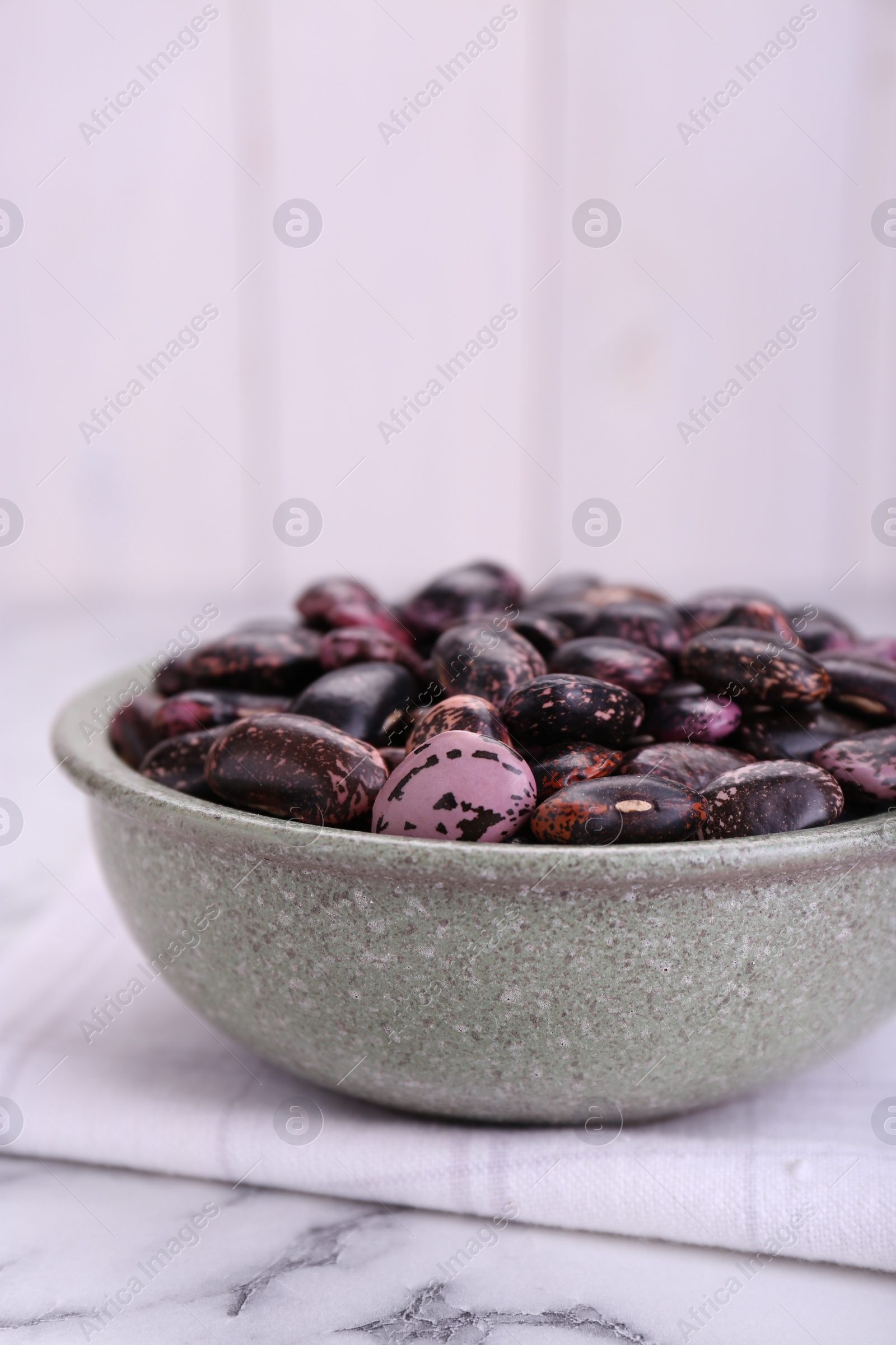 Photo of Bowl with dry kidney beans on white marble table