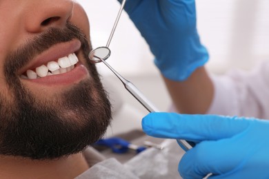 Photo of Dentist examining young man's teeth in clinic, closeup