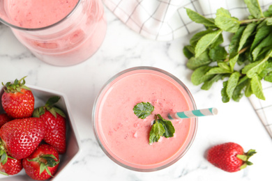 Photo of Tasty strawberry smoothie with mint in glass on white marble table, flat lay