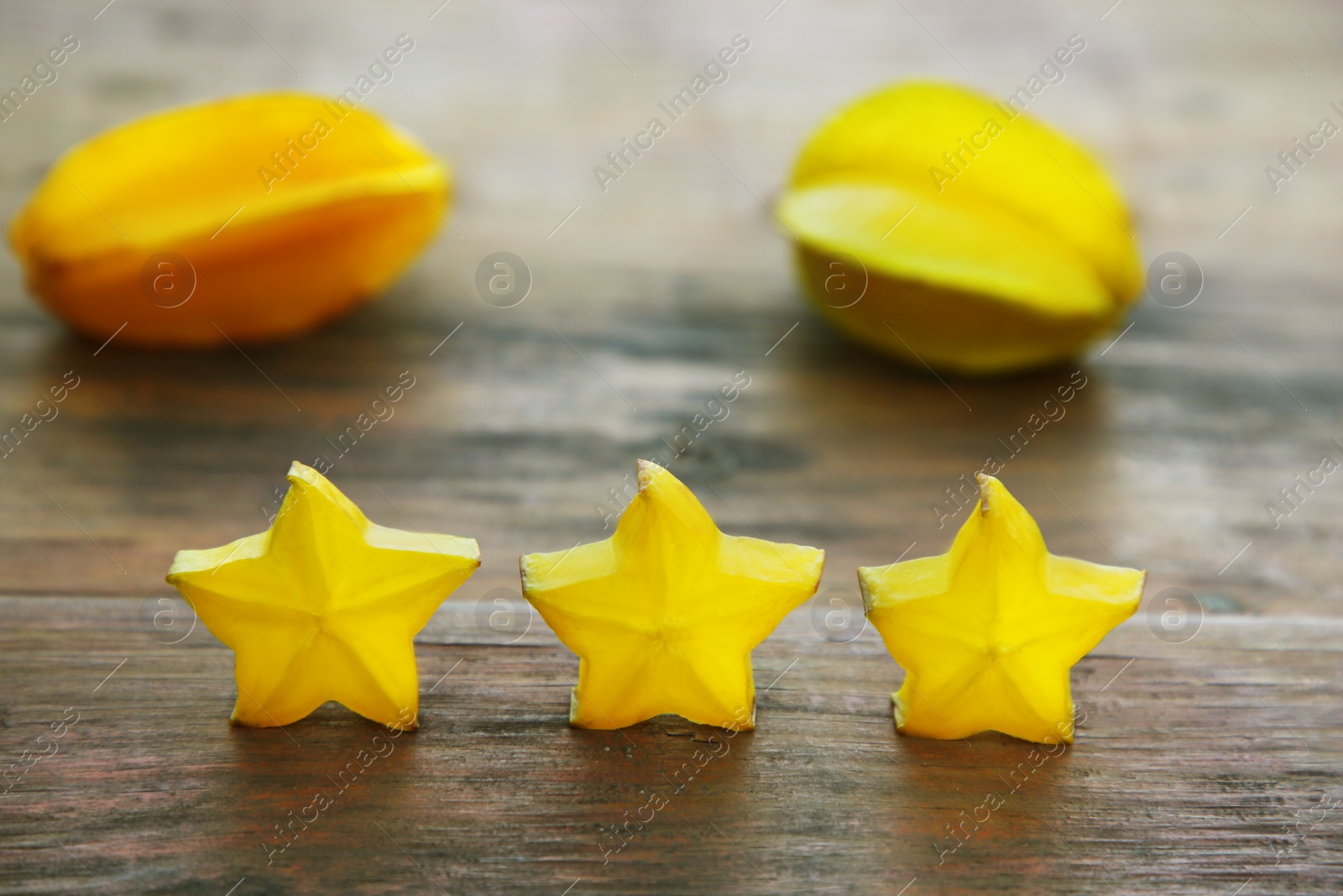 Photo of Delicious cut and whole carambolas on wooden table. Exotic fruit