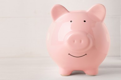 Photo of Ceramic piggy bank on white wooden table, closeup. Space for text