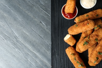 Board with cheese sticks and sauces on table, top view. Space for text