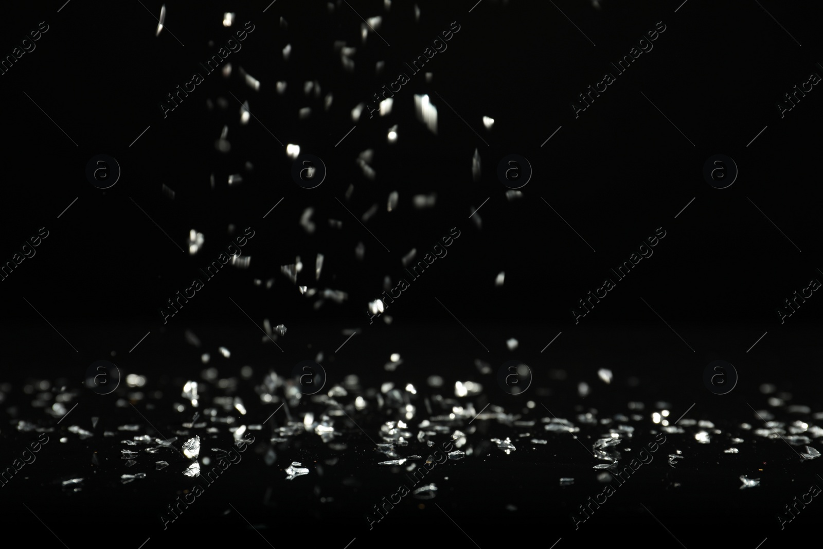 Photo of Shiny silver glitter falling down on black background. Bokeh effect