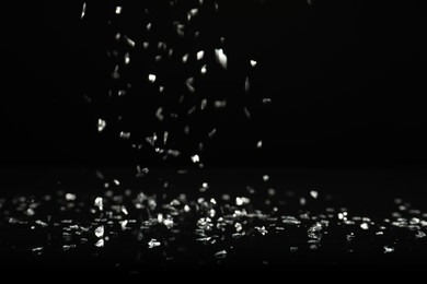 Photo of Shiny silver glitter falling down on black background. Bokeh effect