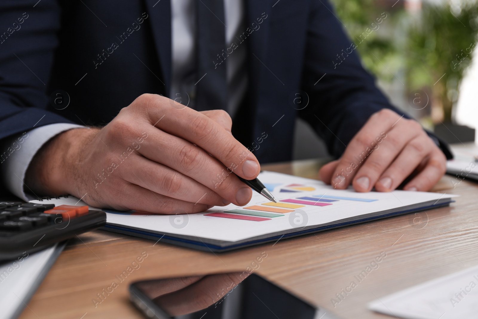 Photo of Businessman working with charts and graphs at table in office, closeup. Investment analysis