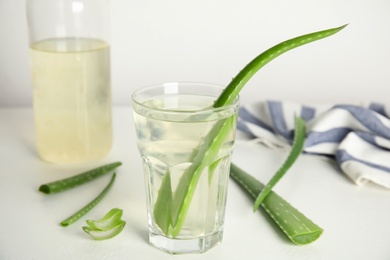 Photo of Fresh aloe drink and leaves on white table