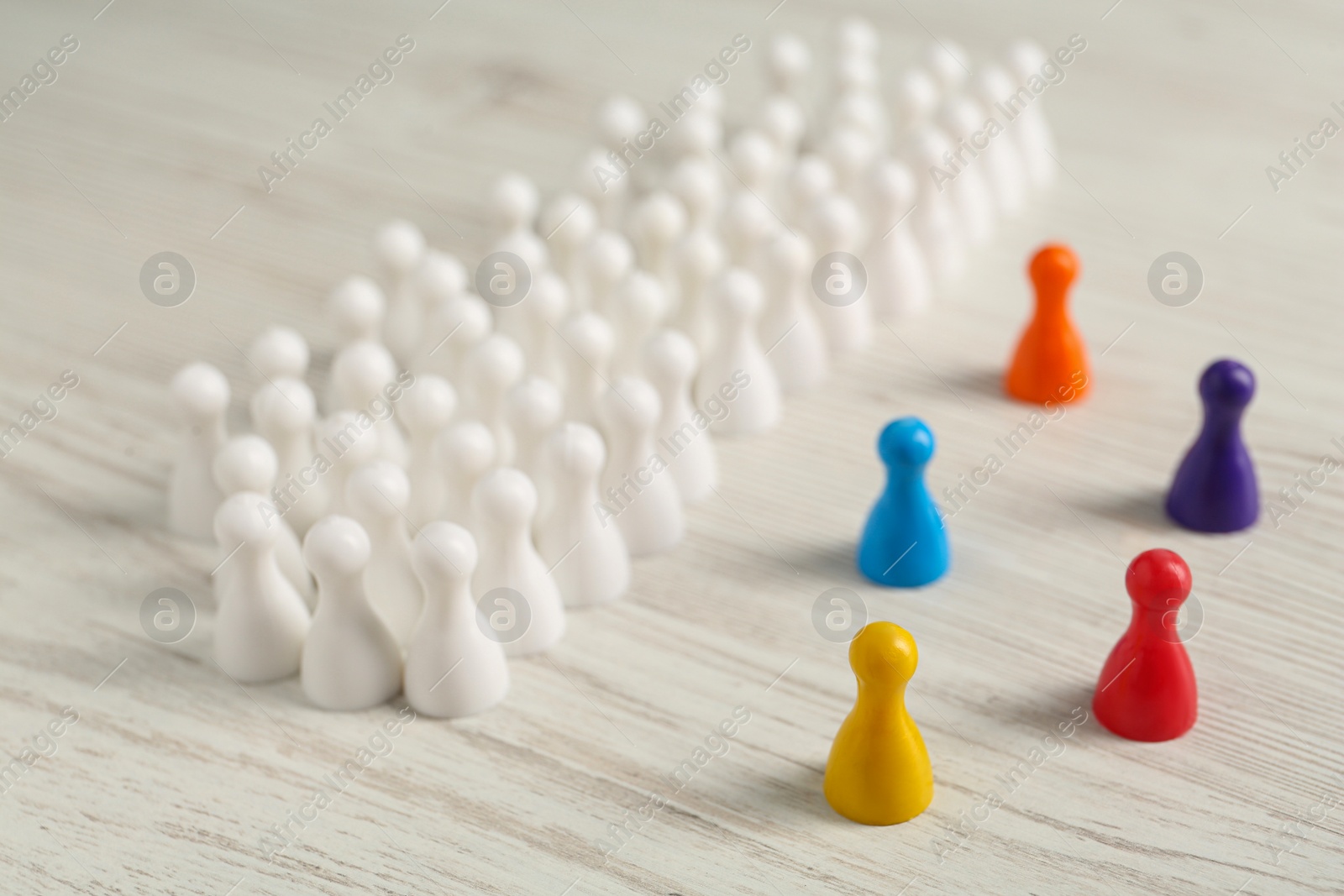 Photo of Colorful pawns on white wooden table. Social inclusion concept