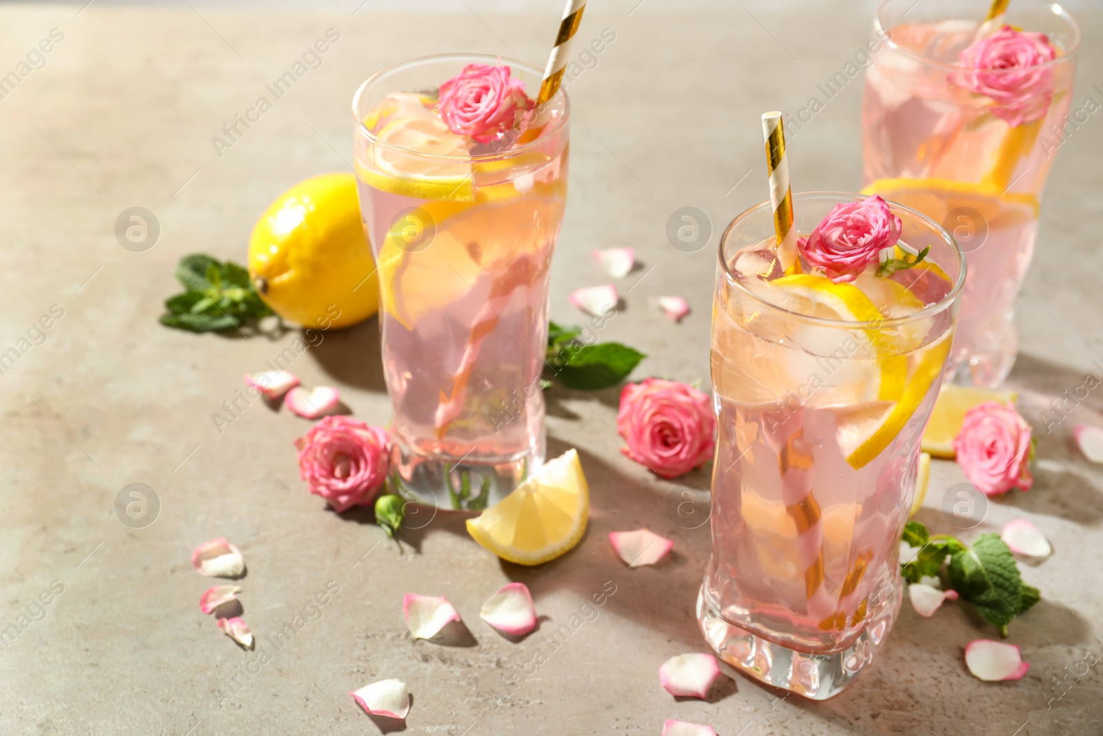 Photo of Delicious refreshing drink with rose flowers and lemon slices on light grey table