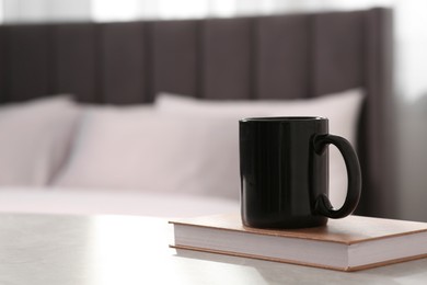 Black ceramic mug and book on table indoors. Mockup for design