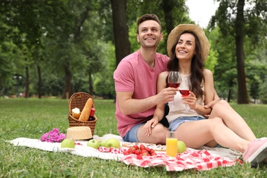 Photo of Happy young couple having picnic in park on summer day