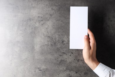 Photo of Man holding blank card at black textured table, top view. Mockup for design