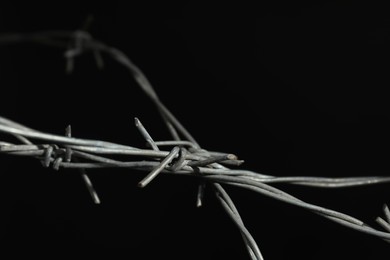 Shiny metal barbed wire on black background, closeup