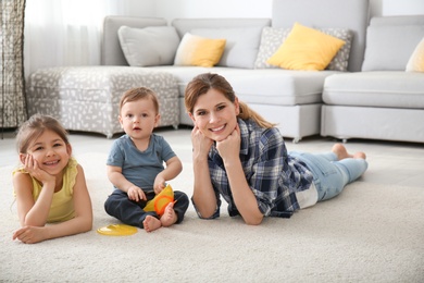 Photo of Mother with cute little children lying on cozy carpet at home