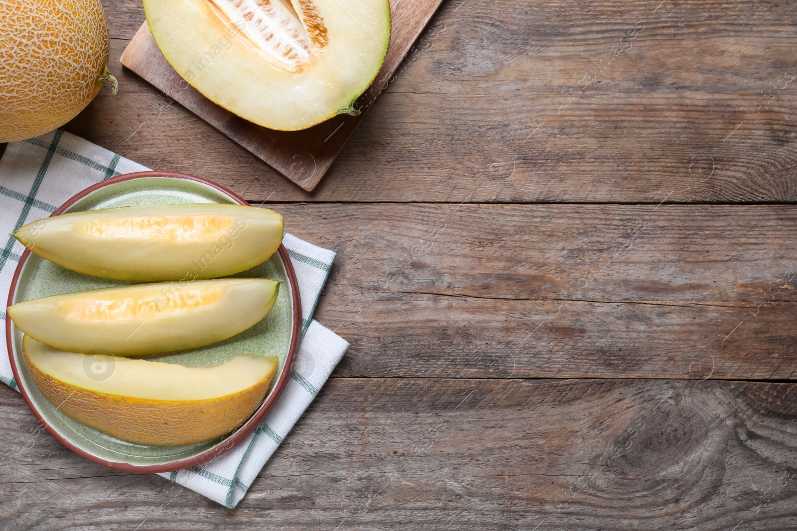 Photo of Pieces of delicious honeydew melon on wooden table, flat lay. Space for text