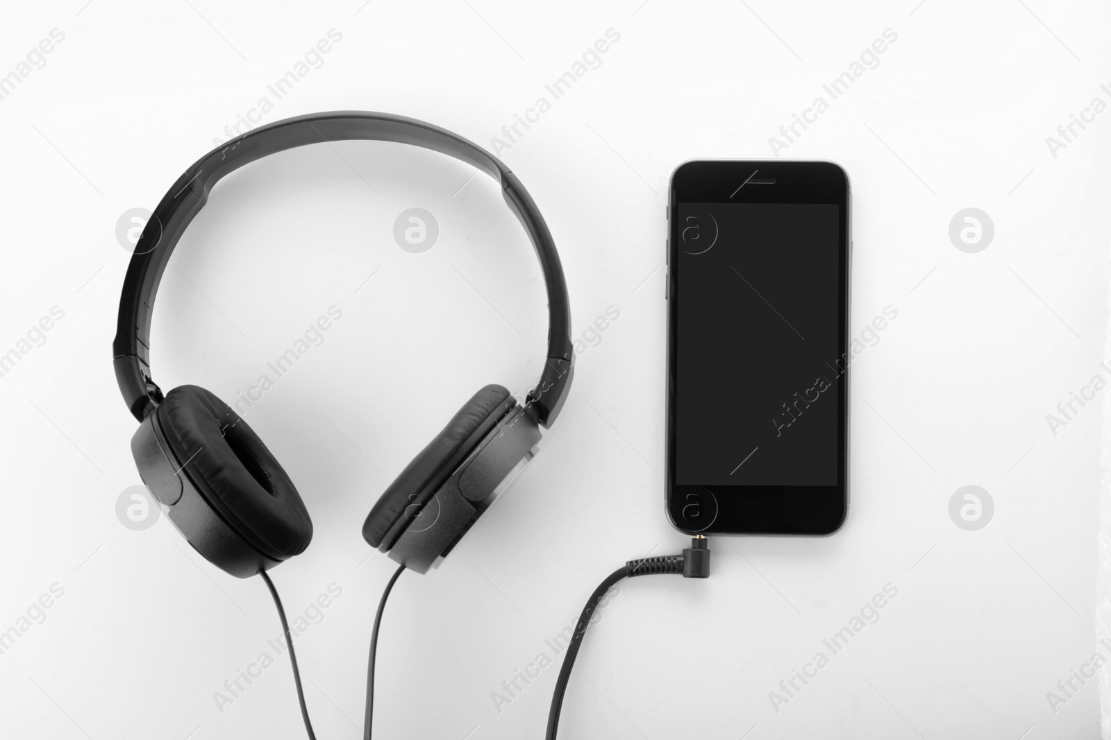 Photo of Smartphone with blank screen and headphones on white background, top view