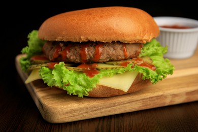 Tasty burger with patty, lettuce and cheese on wooden table, closeup