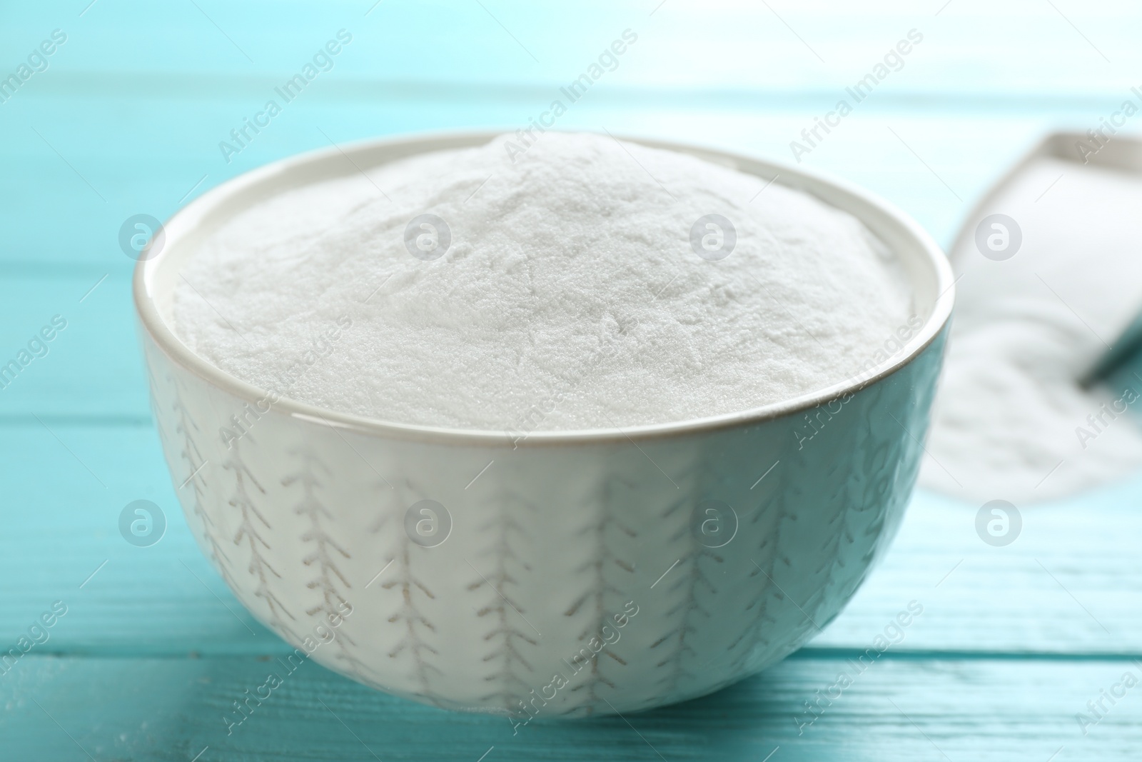 Photo of Baking soda in bowl on blue wooden table