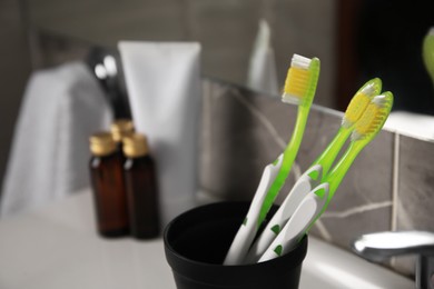 Light green toothbrushes in black toothbrush holder indoors
