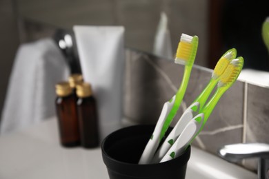 Photo of Light green toothbrushes in black toothbrush holder indoors