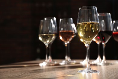 Photo of Different tasty wines in glasses on wooden table, space for text