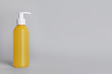 Photo of Bottle of face cleansing product on light grey background. Space for text