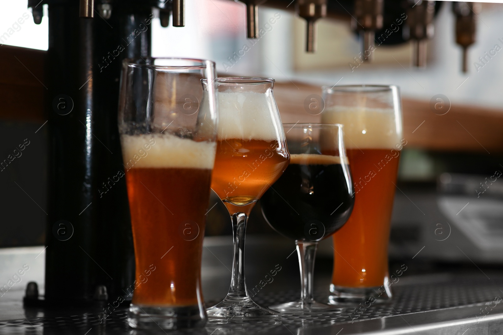 Photo of Different beers in glasses on bar counter