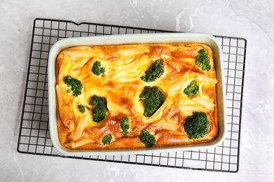 Photo of Tasty broccoli casserole in baking dish on cooling rack, top view