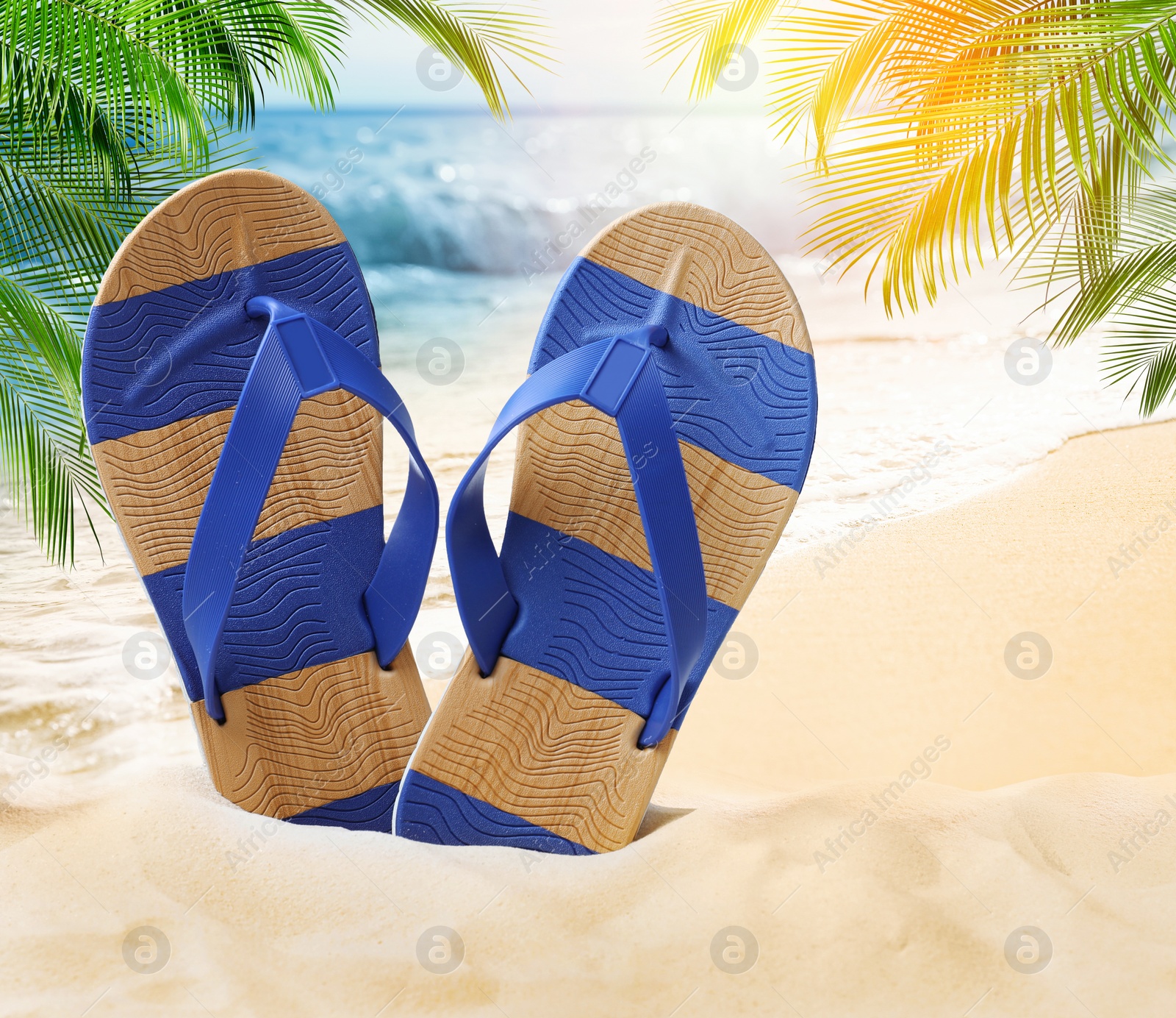 Image of Striped flip flops on sandy beach near sea