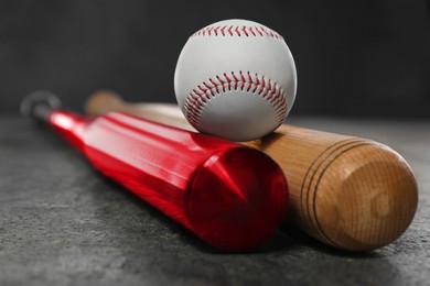 Photo of Baseball bats and ball on grey table, closeup