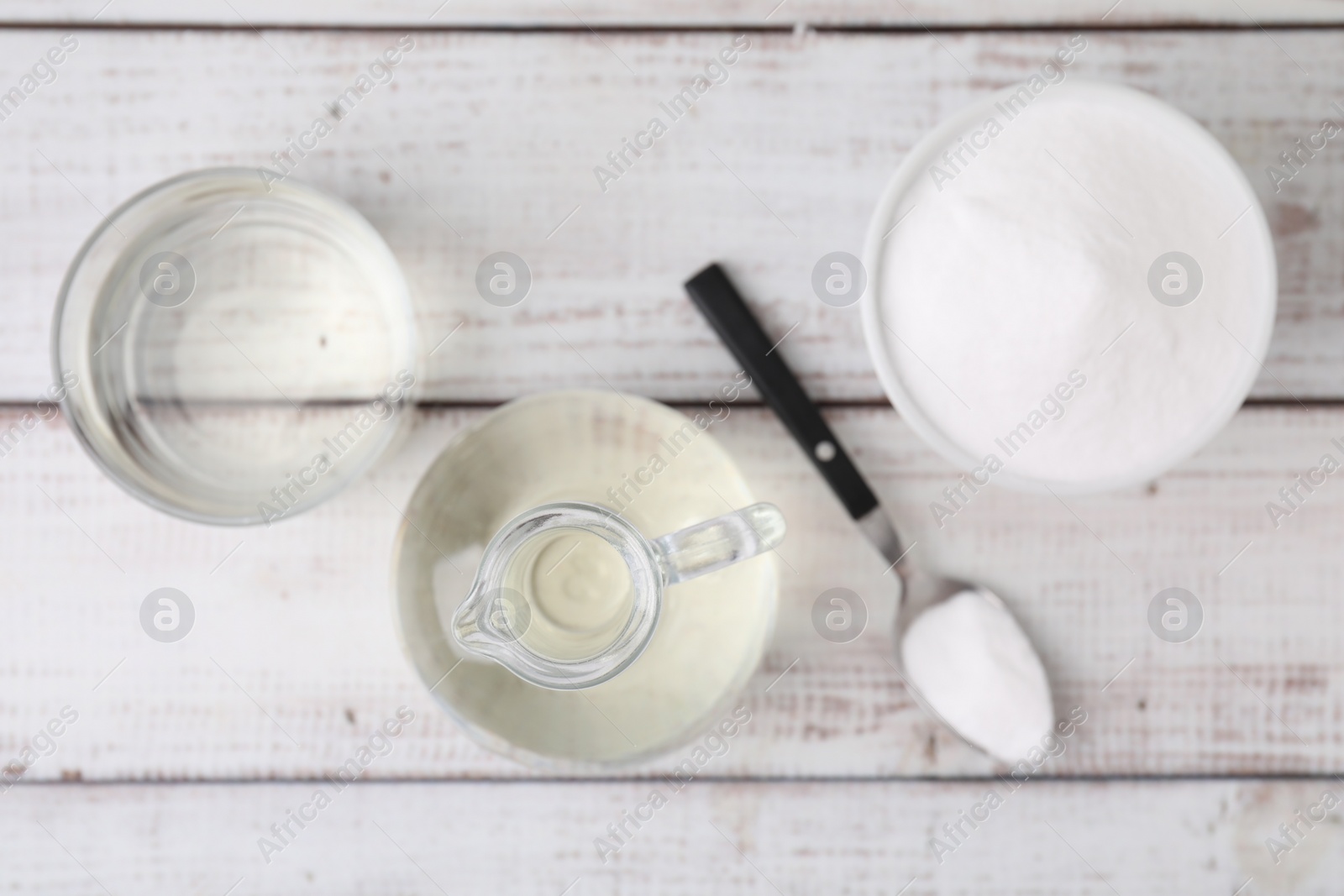 Photo of Vinegar and baking soda on white wooden table, flat lay