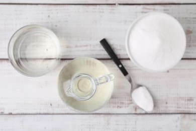 Vinegar and baking soda on white wooden table, flat lay