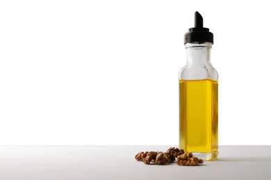 Bottle of cooking oil and walnuts on white background, space for text