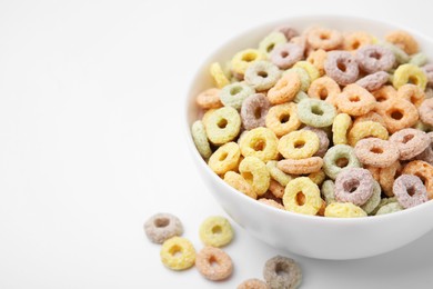 Photo of Tasty cereal rings in bowl on white table, closeup. Space for text