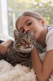 Photo of Cute little girl with her cat at home. Childhood pet