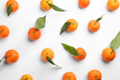 Photo of Fresh ripe tangerines with green leaves on white background, top view